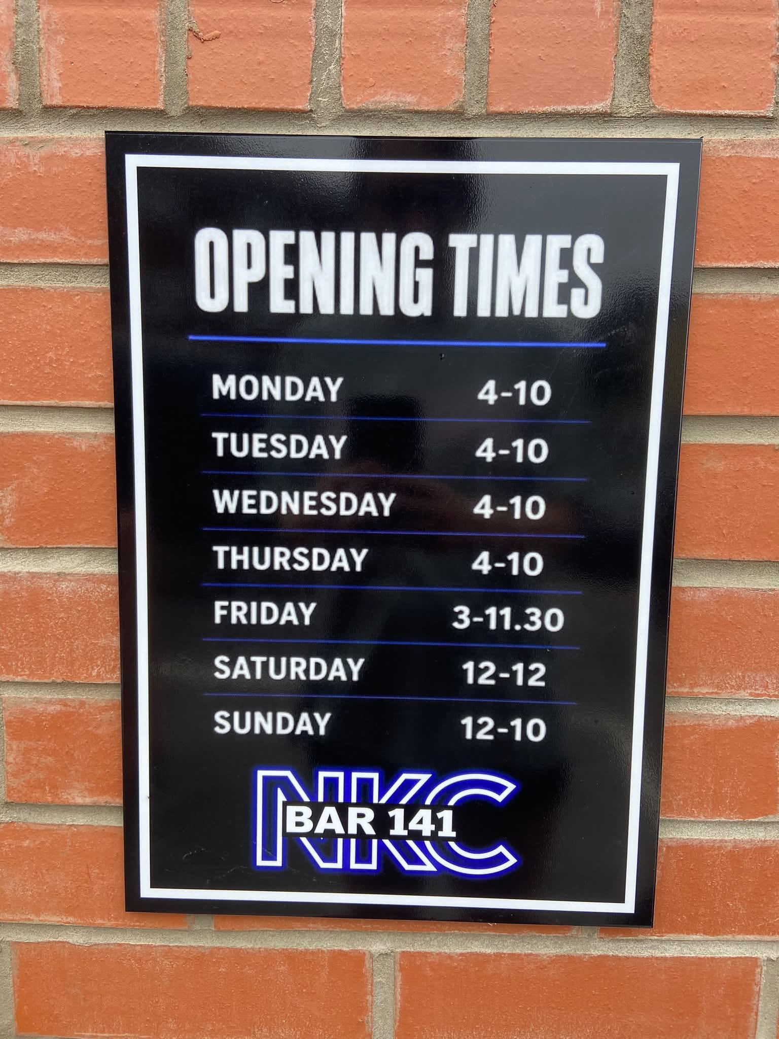 Official NKC Bar 141 Opening Times Plaque on the brick wall